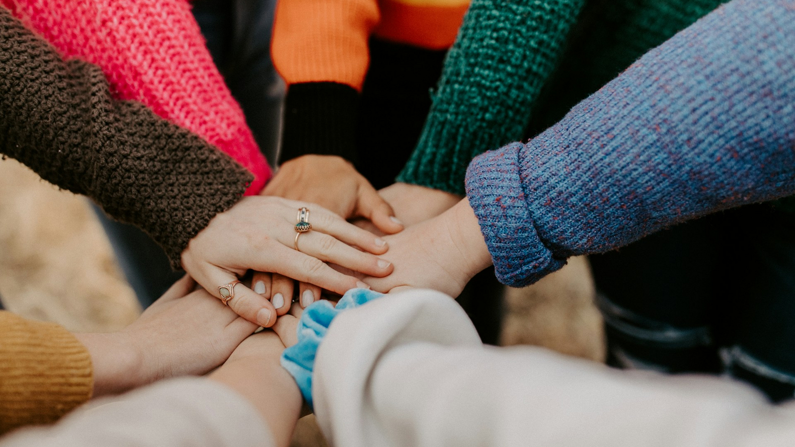 People in a circle putting their hands together in the middle