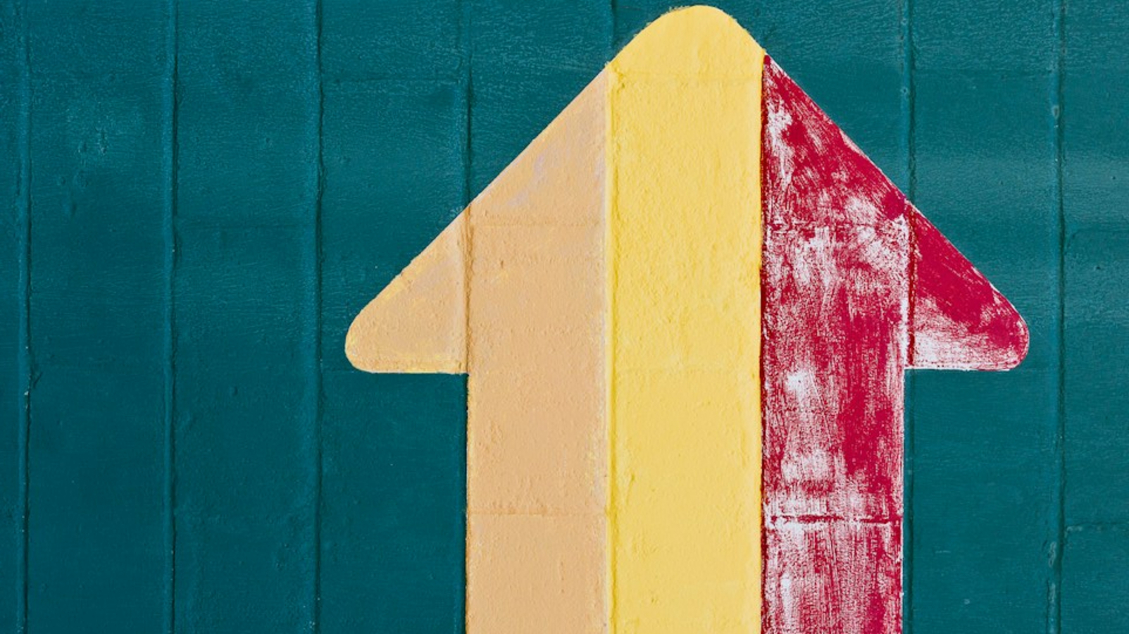 Multicoloured arrow pointing upwards painted on wall