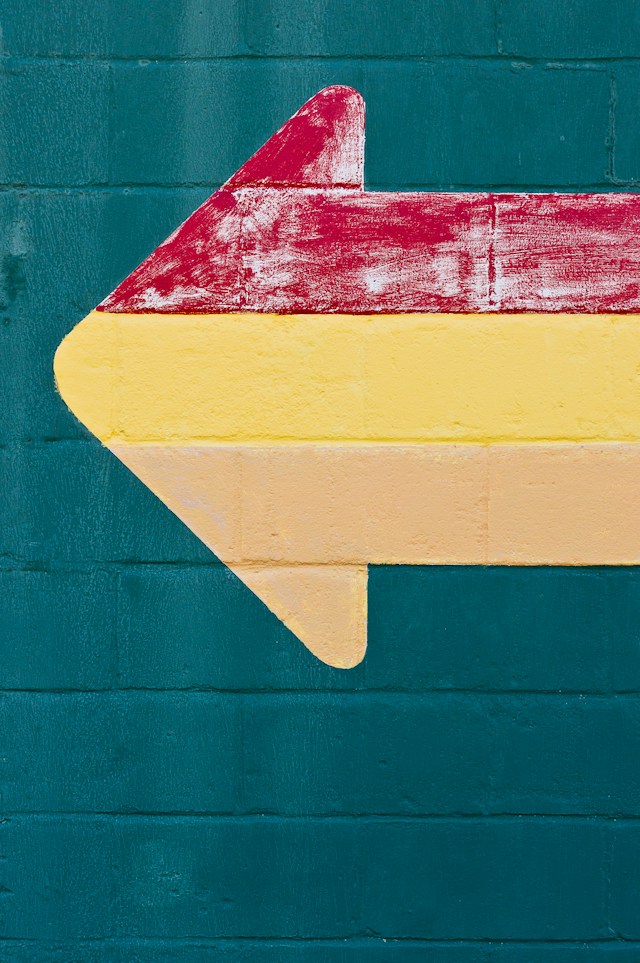 Multicoloured arrow pointing upwards painted on wall